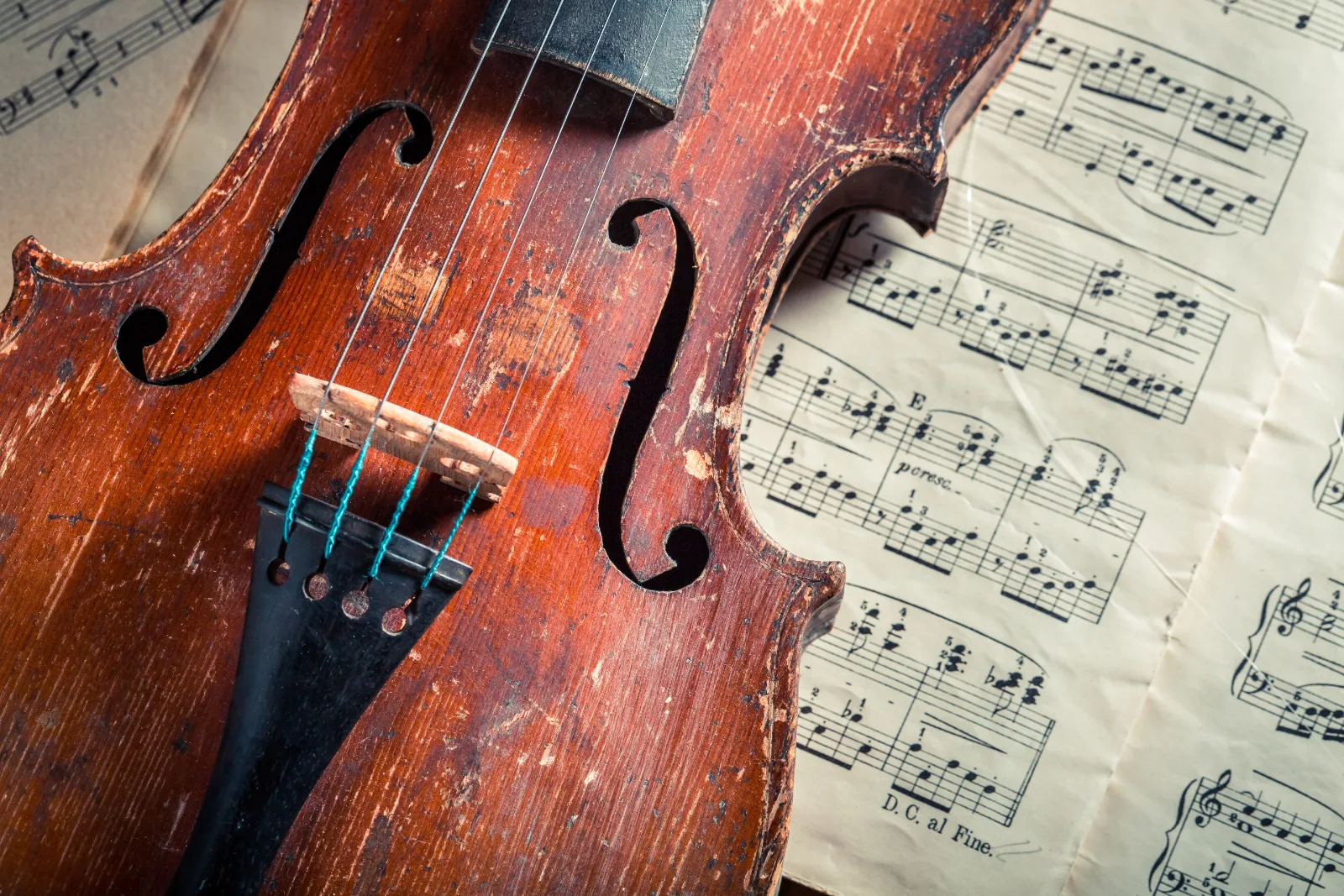 Antique violin resting on a page of aged handwritten sheet music.