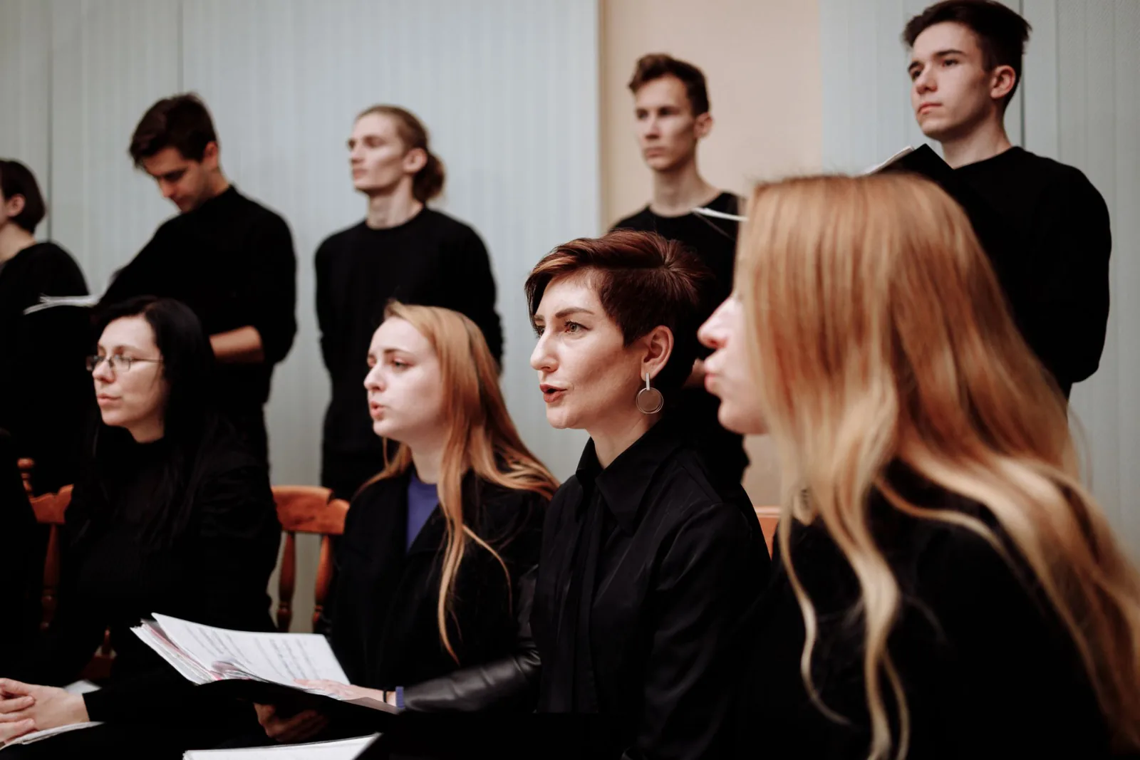 Choir of singers dressed in black performing sacred choral music.
